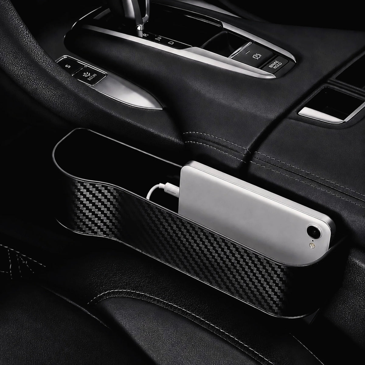 Rangement de fente de siège voiture positionné côté conducteur avec un téléphone en charge à l'intérieur.
